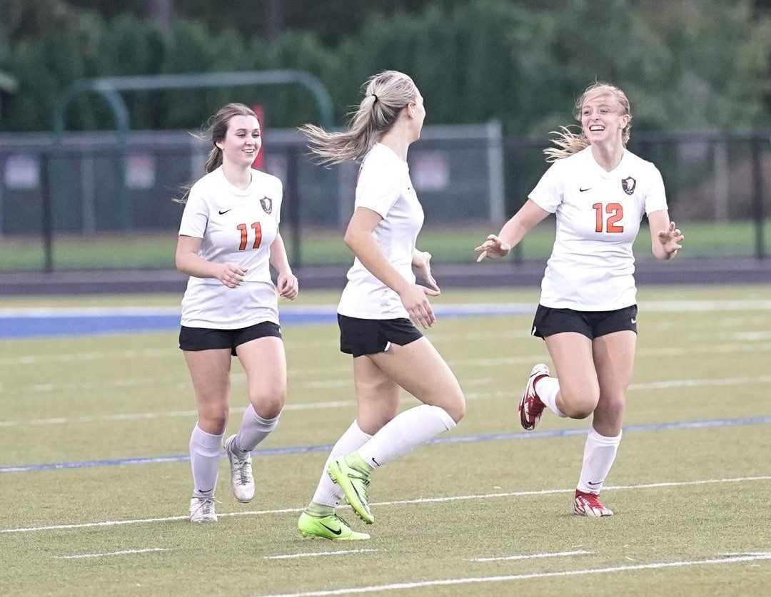 Gladstone's Rhyli Grim (12) is greeted by Sam Jedrykowski (11) and Alyx DeVeny after scoring Tuesday. (Photo by Jon Olson)