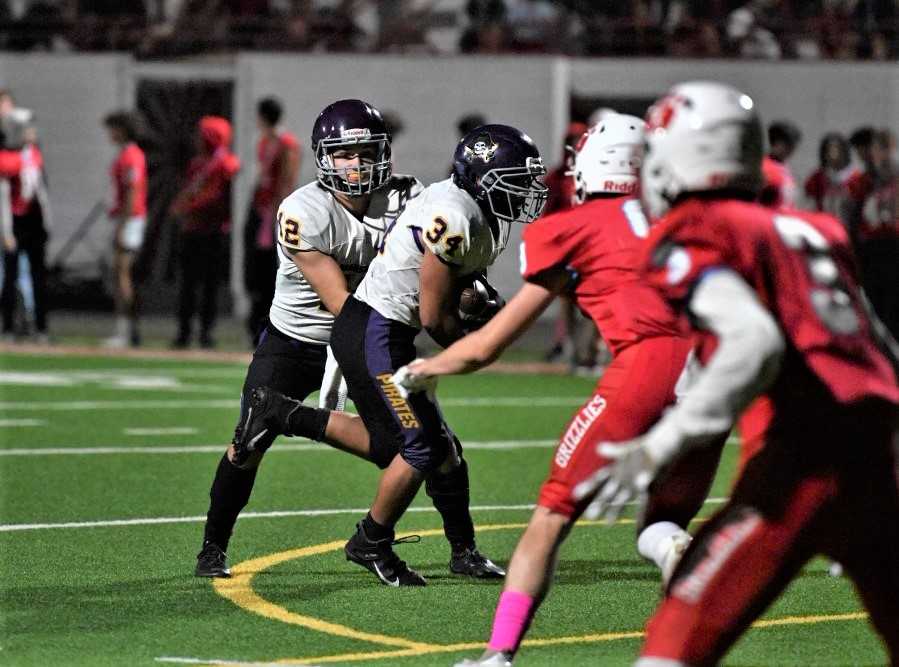 Marshfield quarterback Landon Croff (12) hands to John Lemmons (34) in last week's win at Ashland. (Photo by Antonio Gallagher)