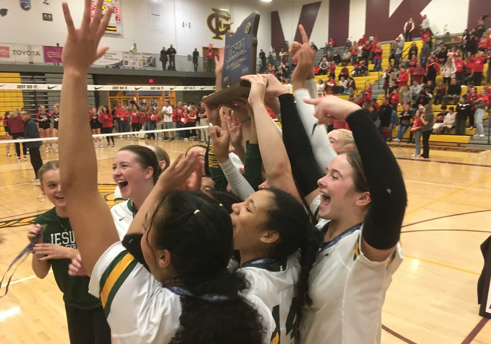 Jesuit's volleyball team celebrates with the state championship trophy after defeating Oregon City on Saturday night.