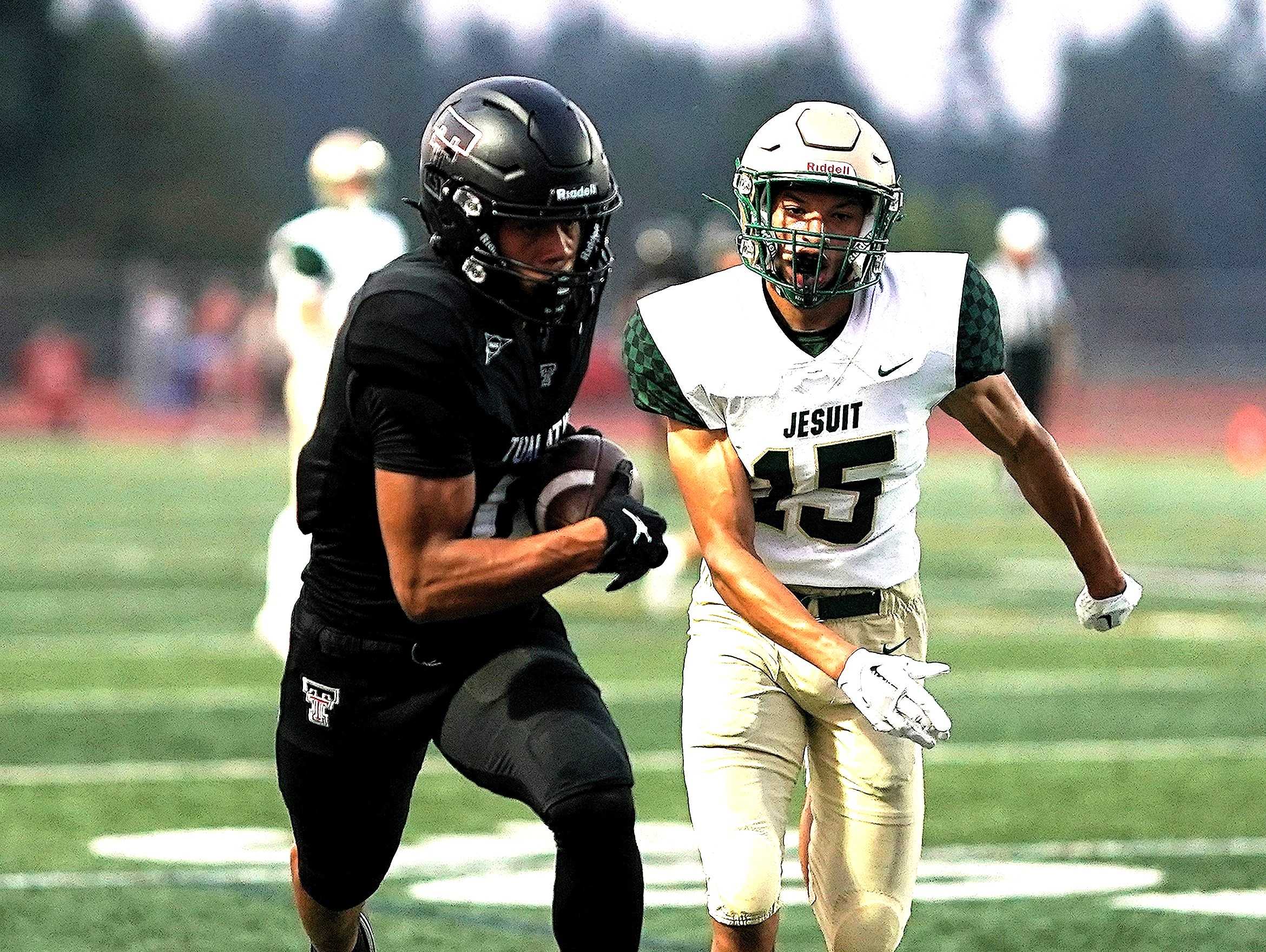 Tualatin's Zhaiel Smith, evading Jesuit's Chris Lowe (15), had three touchdowns catches in Friday's win. (Photo by J.R. Olson)