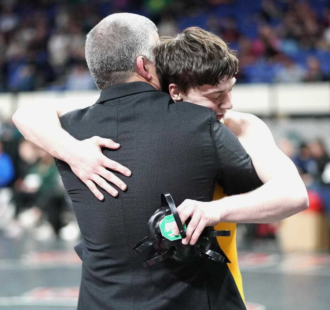 Newberg senior Gus Amerson embraces coach Neil Russo after winning the title at 157 pounds Saturday. (Photo by J.R. Olson)