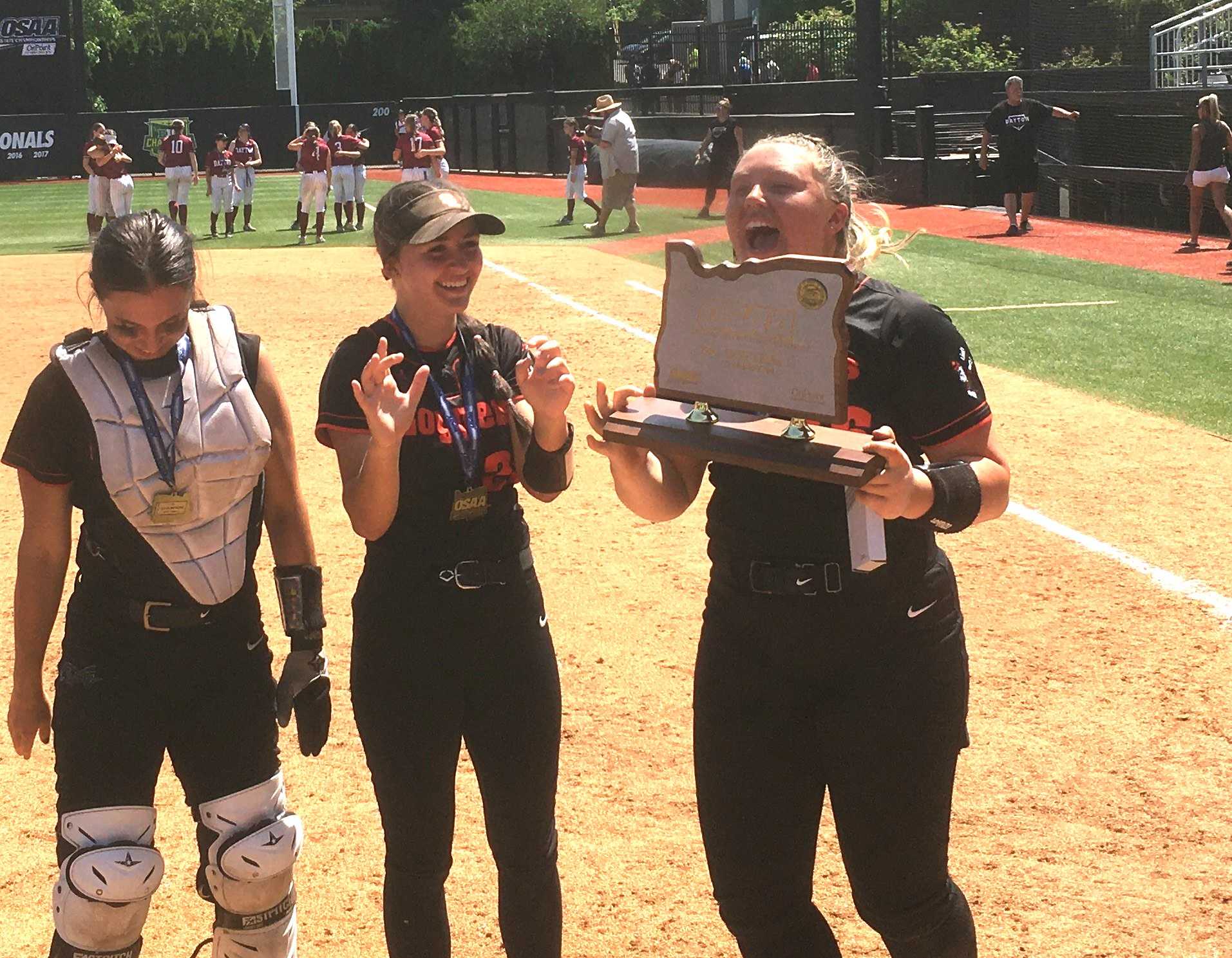 Scio senior pitcher Myleigh Cooper holds the state championship trophy after beating Dayton 9-3 on Friday.