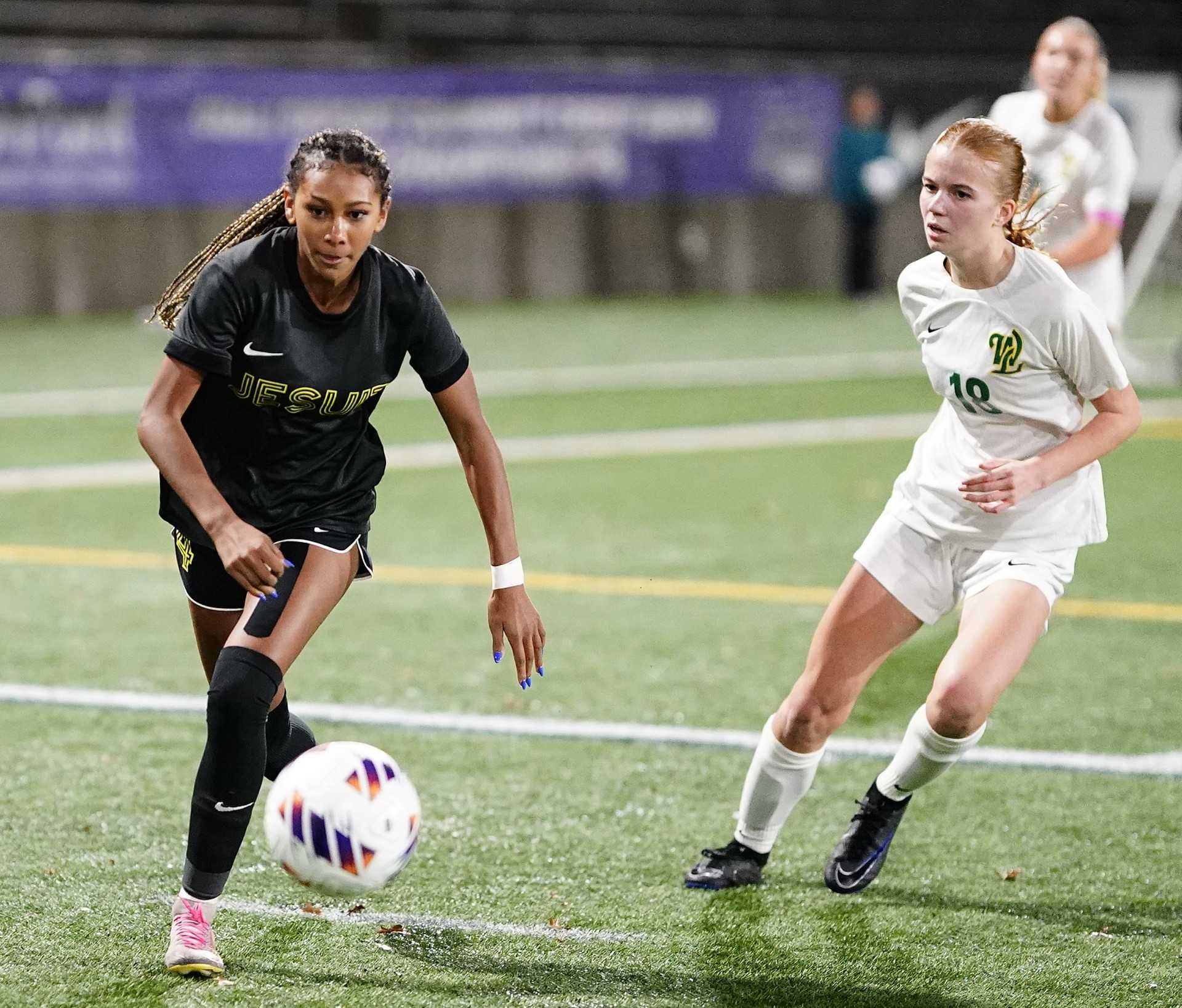 Jesuit's Eva Hairston (left) dribbles past West Linn's Chloe An in Saturday night's 6A girls soccer final. (Photo by J.R. Olson)