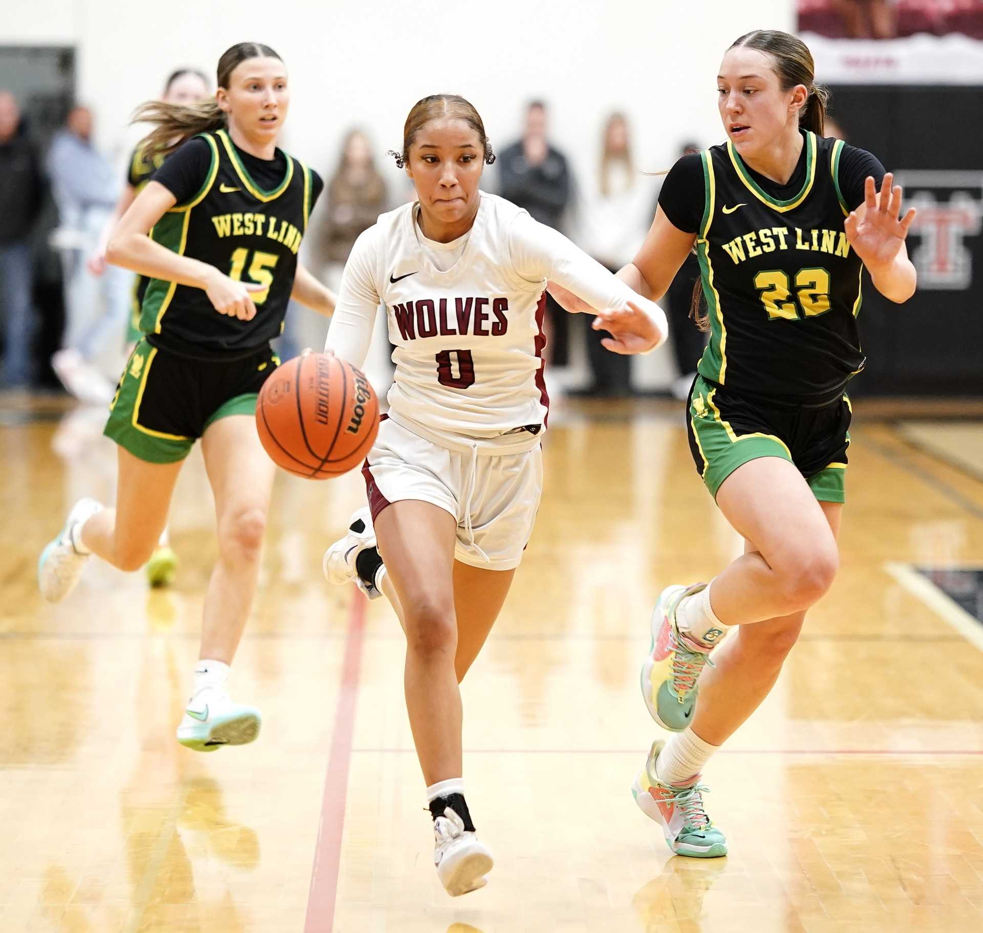 Tualatin's Bella Amens (0) races up the floor against West Linn's Kaylor Buse (22) in Friday night's game. (Photo by J.R. Olson)