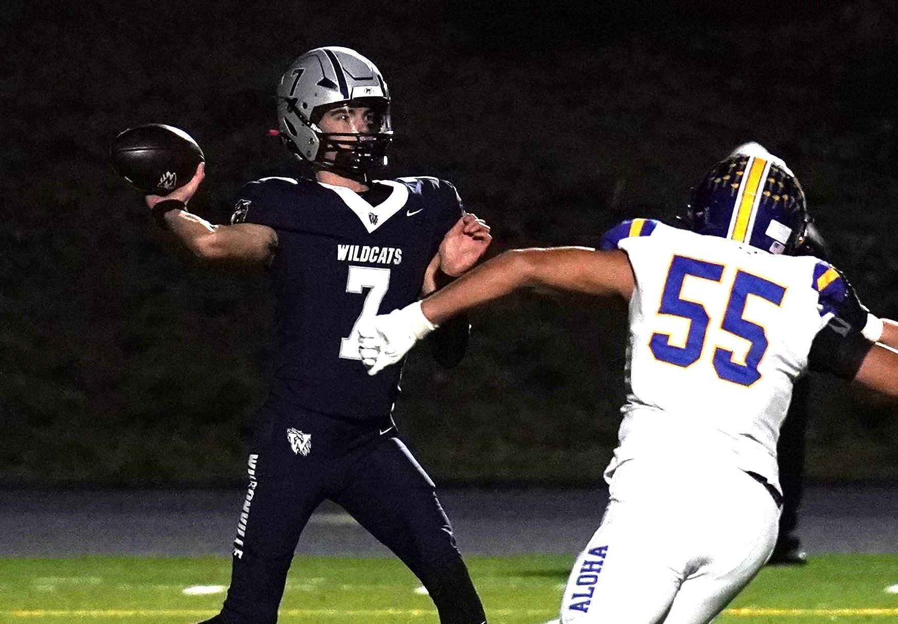 Wilsonville's Trevor Glos (7), rushed by Aloha's Marcos Ruiz Verdin, passed for 238 yards in Friday's win. (Photo by JR Olson)