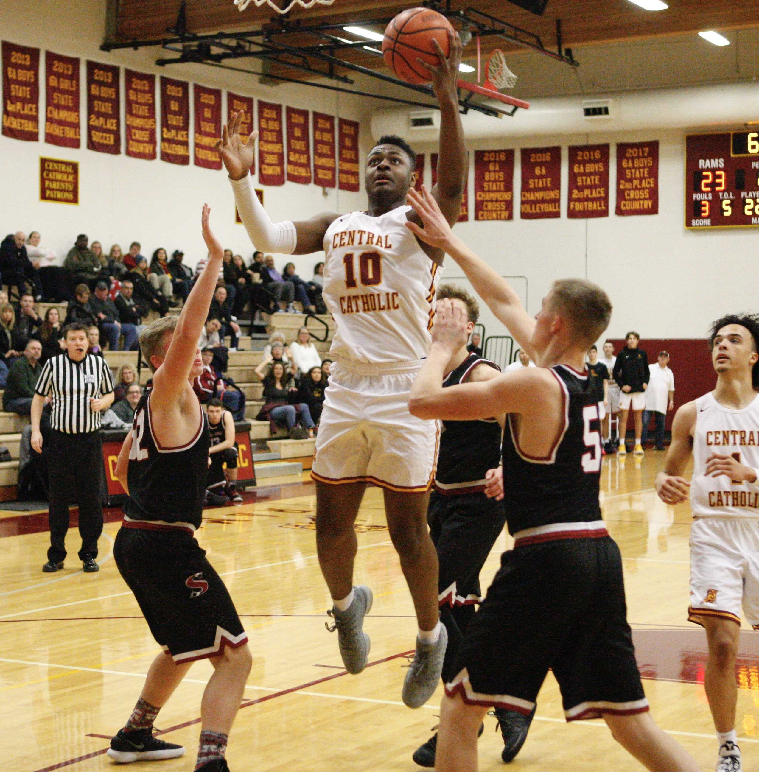 Central Catholic junior SataieVior Ayilola skies over three Sandy defenders for two of his 17 points.